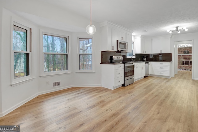 kitchen featuring appliances with stainless steel finishes, decorative light fixtures, decorative backsplash, and white cabinets