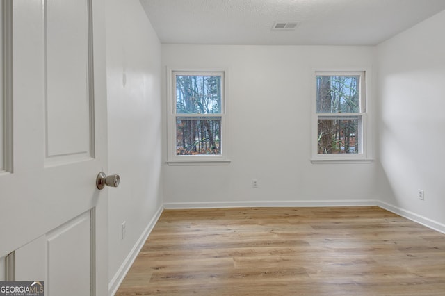 spare room with light hardwood / wood-style floors and a textured ceiling