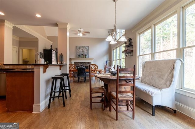 dining space with crown molding, ceiling fan with notable chandelier, and light hardwood / wood-style flooring