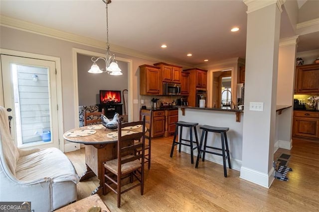 dining space featuring crown molding, light hardwood / wood-style flooring, and a chandelier