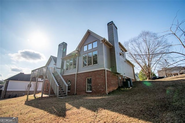 rear view of property featuring central AC unit, a deck, and a lawn