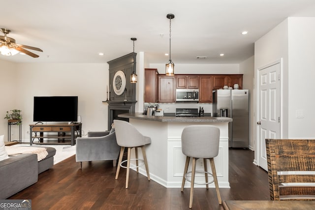 kitchen featuring stainless steel appliances, a breakfast bar, pendant lighting, and dark wood-type flooring