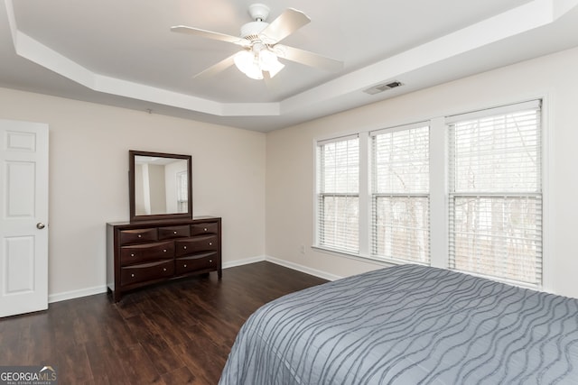 bedroom featuring dark hardwood / wood-style floors, ceiling fan, and a tray ceiling