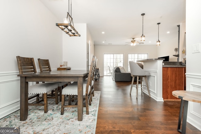 dining area featuring dark hardwood / wood-style floors, ceiling fan, and bar area