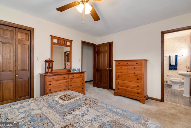 bedroom featuring ensuite bathroom, light colored carpet, and ceiling fan