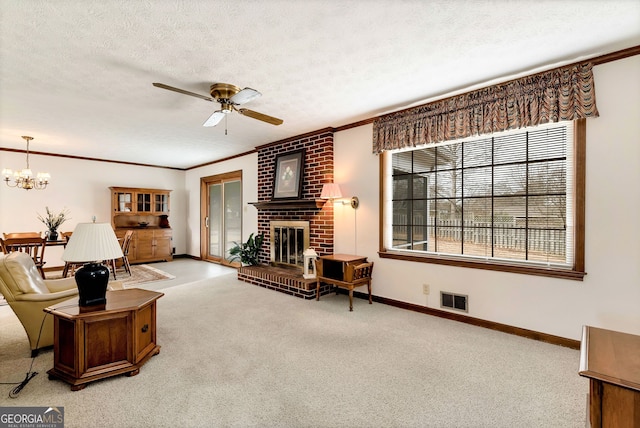 carpeted living room featuring crown molding, a brick fireplace, ceiling fan with notable chandelier, and a textured ceiling