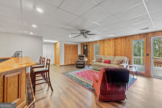 living room with a paneled ceiling, wooden walls, and hardwood / wood-style floors