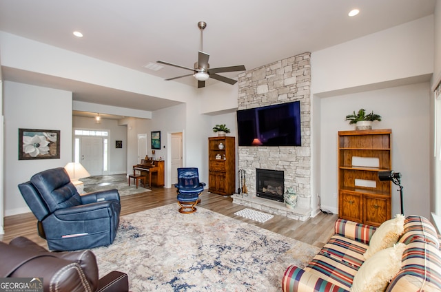 living room featuring ceiling fan, a fireplace, and light hardwood / wood-style floors