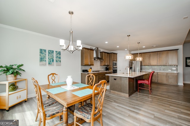 dining room with ornamental molding, sink, a notable chandelier, and light hardwood / wood-style flooring