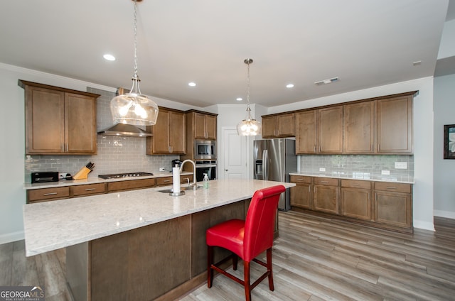 kitchen featuring a kitchen island with sink, sink, stainless steel appliances, and a kitchen breakfast bar