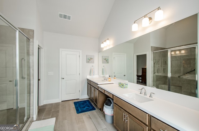 bathroom with lofted ceiling, vanity, and a shower with door