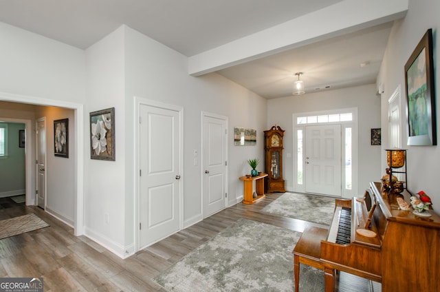 foyer entrance with beamed ceiling and light hardwood / wood-style floors