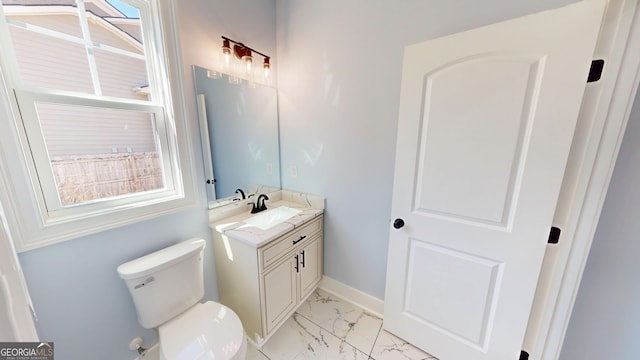 half bathroom with baseboards, marble finish floor, vanity, and toilet