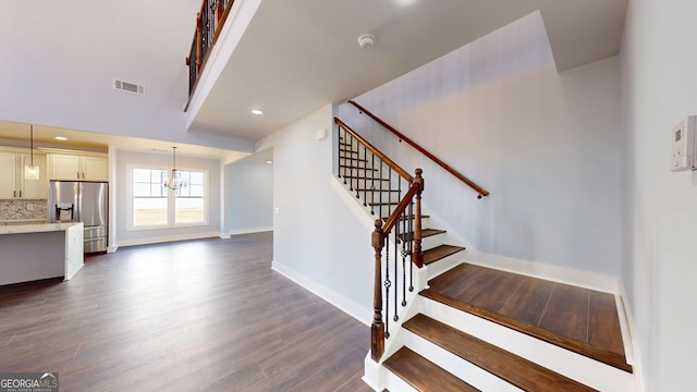 staircase with wood finished floors, visible vents, baseboards, an inviting chandelier, and recessed lighting