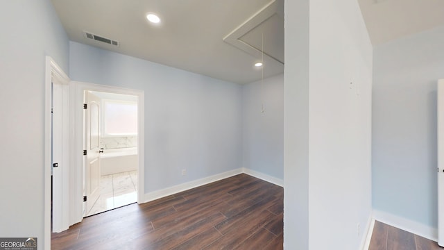 empty room featuring baseboards, visible vents, dark wood finished floors, attic access, and recessed lighting