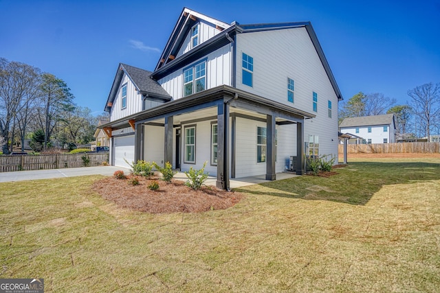 view of side of home featuring board and batten siding, fence, a lawn, a garage, and driveway