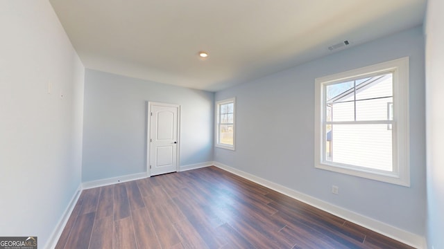 empty room with visible vents, dark wood-style floors, and baseboards