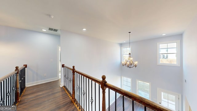 corridor with visible vents, an upstairs landing, dark wood finished floors, baseboards, and a chandelier