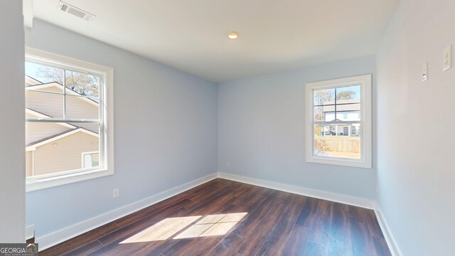 empty room with plenty of natural light, baseboards, and wood finished floors