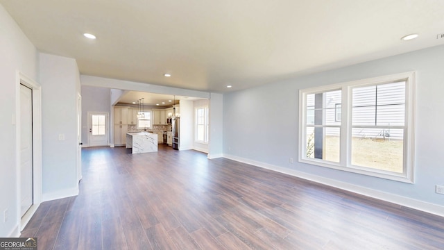 unfurnished living room with recessed lighting, baseboards, and dark wood-style flooring