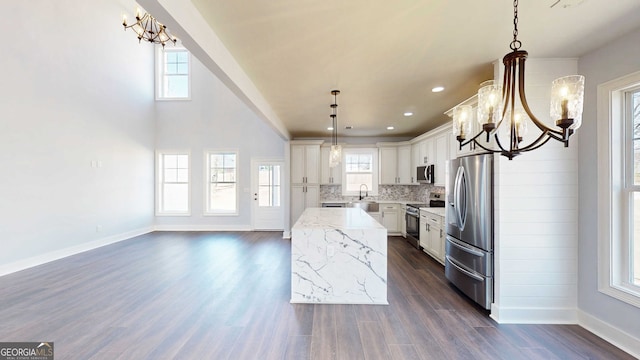 kitchen with a kitchen island, decorative backsplash, a notable chandelier, stainless steel appliances, and a sink
