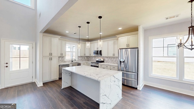 kitchen featuring tasteful backsplash, a notable chandelier, appliances with stainless steel finishes, and dark wood-style flooring