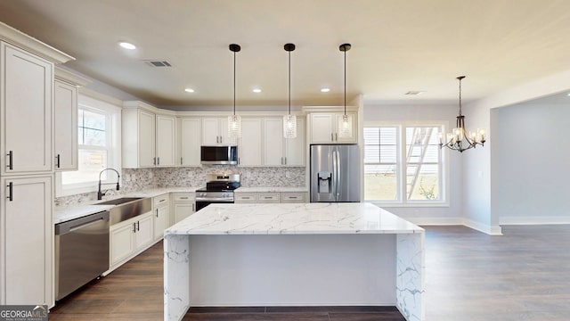 kitchen featuring visible vents, a center island, decorative backsplash, appliances with stainless steel finishes, and a sink