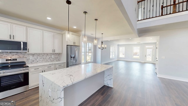 kitchen with a kitchen island, stainless steel appliances, open floor plan, backsplash, and a chandelier