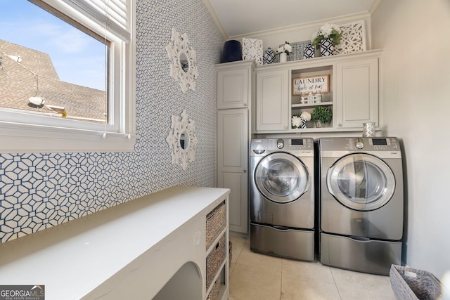 washroom with ornamental molding, washing machine and dryer, light tile patterned flooring, and cabinets