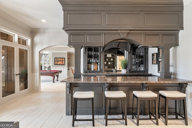 bar featuring french doors, billiards, crown molding, light wood-type flooring, and dark stone countertops