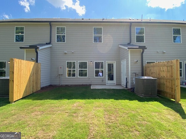 back of property featuring cooling unit and a lawn