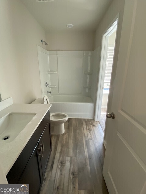 full bathroom featuring vanity, hardwood / wood-style floors, shower / tub combination, and toilet