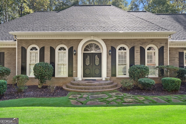 exterior space with roof with shingles, brick siding, and a lawn