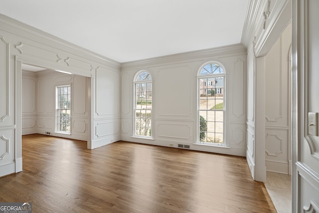 foyer featuring ornamental molding, visible vents, a decorative wall, and dark wood-style floors