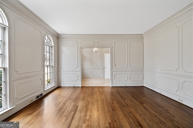 interior space with wood finished floors, visible vents, and a decorative wall