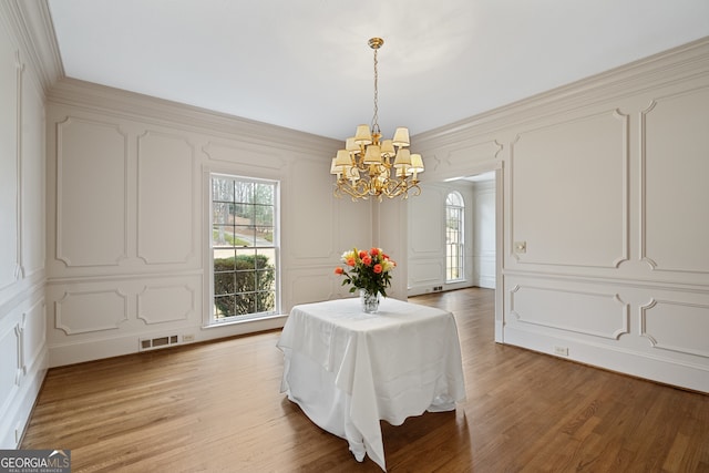 dining room featuring a wealth of natural light, light wood-type flooring, visible vents, and a decorative wall