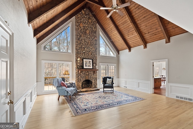 living area featuring light wood-type flooring, wood ceiling, a decorative wall, and a stone fireplace