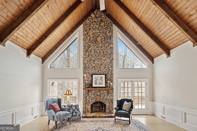 living area with light wood-style floors, wood ceiling, a fireplace, and a decorative wall