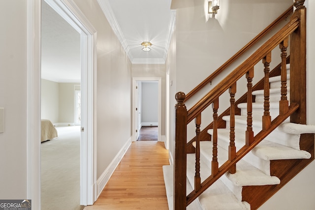 hall featuring light wood finished floors, ornamental molding, stairway, and baseboards