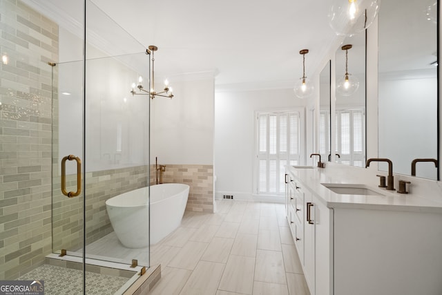 full bathroom featuring double vanity, ornamental molding, a freestanding tub, and a sink