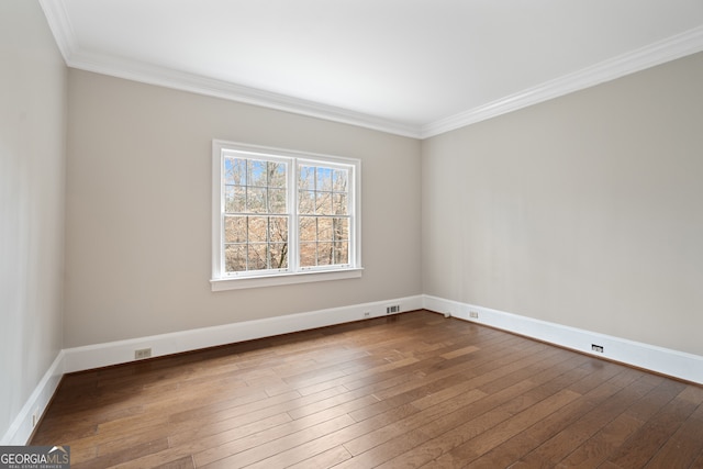 spare room featuring ornamental molding, wood finished floors, visible vents, and baseboards