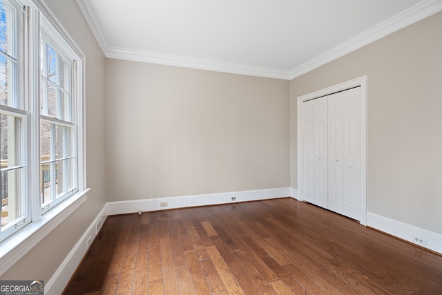 unfurnished bedroom with a closet, baseboards, dark wood-style flooring, and ornamental molding