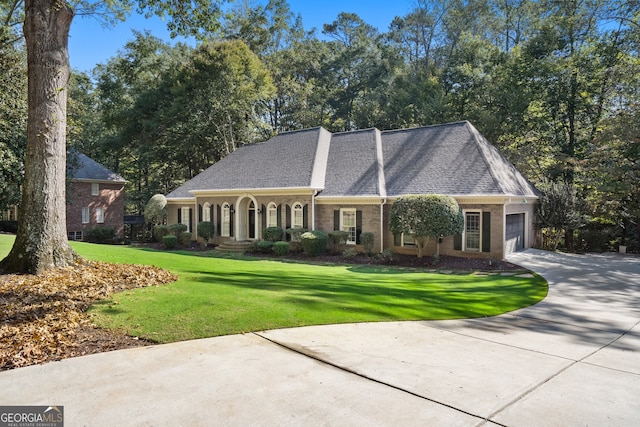 view of front facade featuring a garage, a front yard, concrete driveway, and roof with shingles