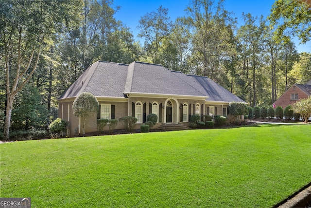 view of front of home with roof with shingles and a front yard