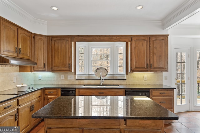 kitchen featuring brown cabinetry, a center island, under cabinet range hood, and black appliances