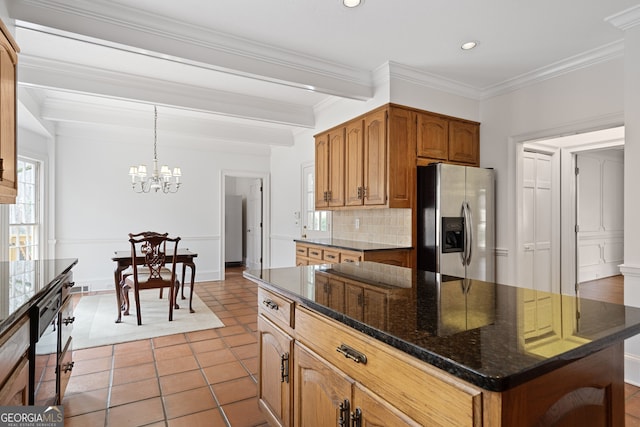 kitchen with tasteful backsplash, brown cabinetry, stainless steel fridge with ice dispenser, a center island, and hanging light fixtures