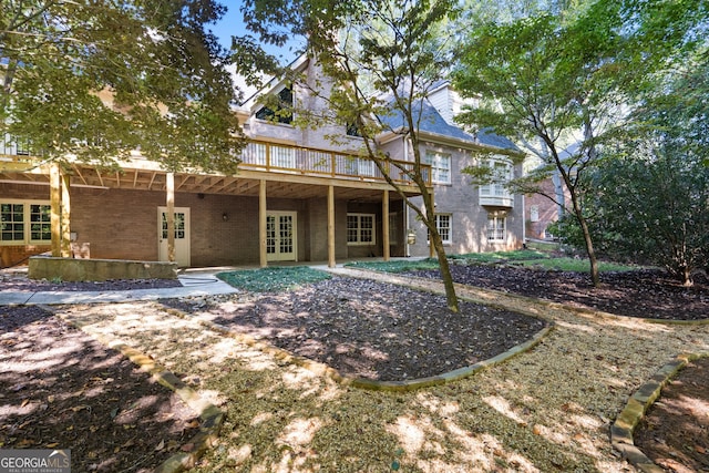 rear view of house featuring brick siding, a deck, and french doors