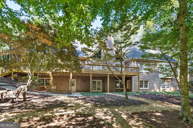 rear view of property with french doors, brick siding, a chimney, and a wooden deck