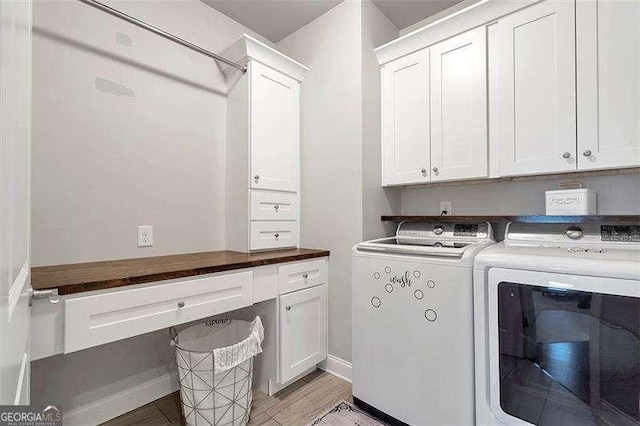 laundry area with cabinets, washing machine and clothes dryer, and light hardwood / wood-style floors