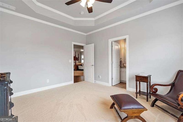 living area with light carpet, a tray ceiling, crown molding, and ceiling fan